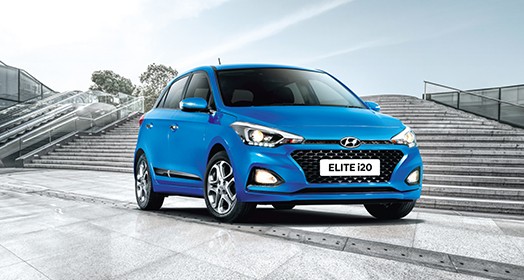 A man getting to the passenger's seat of red Elite i20 parked in front of yellow building