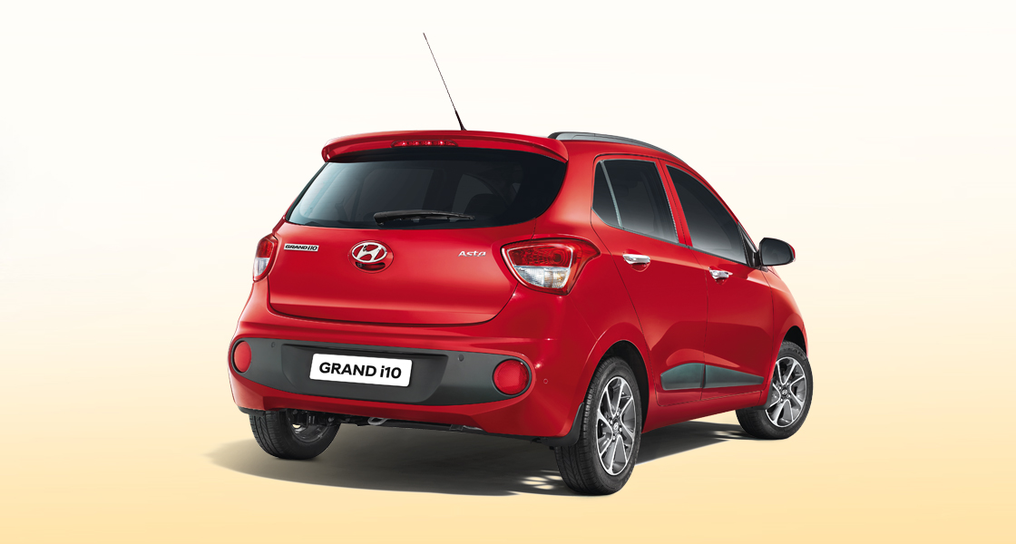 Side view of tangerine orange Grand i10 on a clear day
