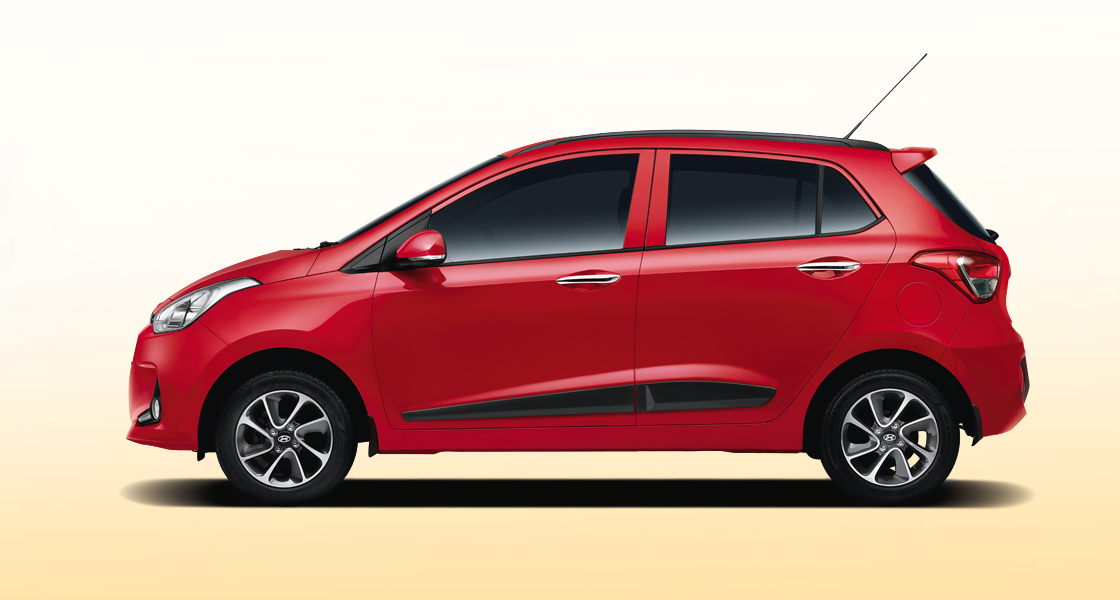 Side view of tangerine orange Grand i10 on a clear day