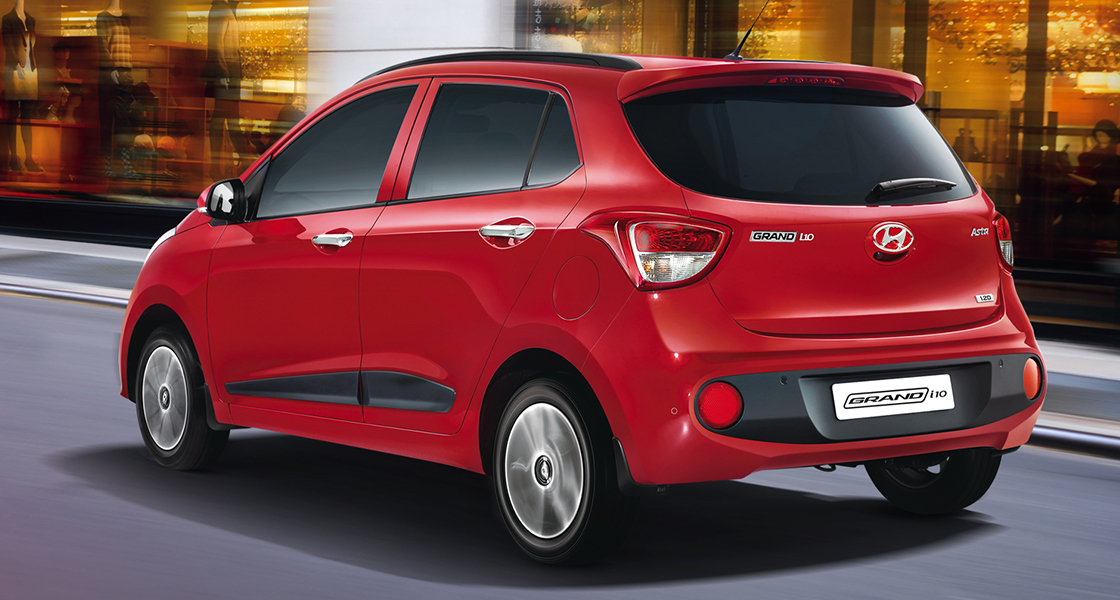 Side-front view of orange Grandi10 with lakeside view at night